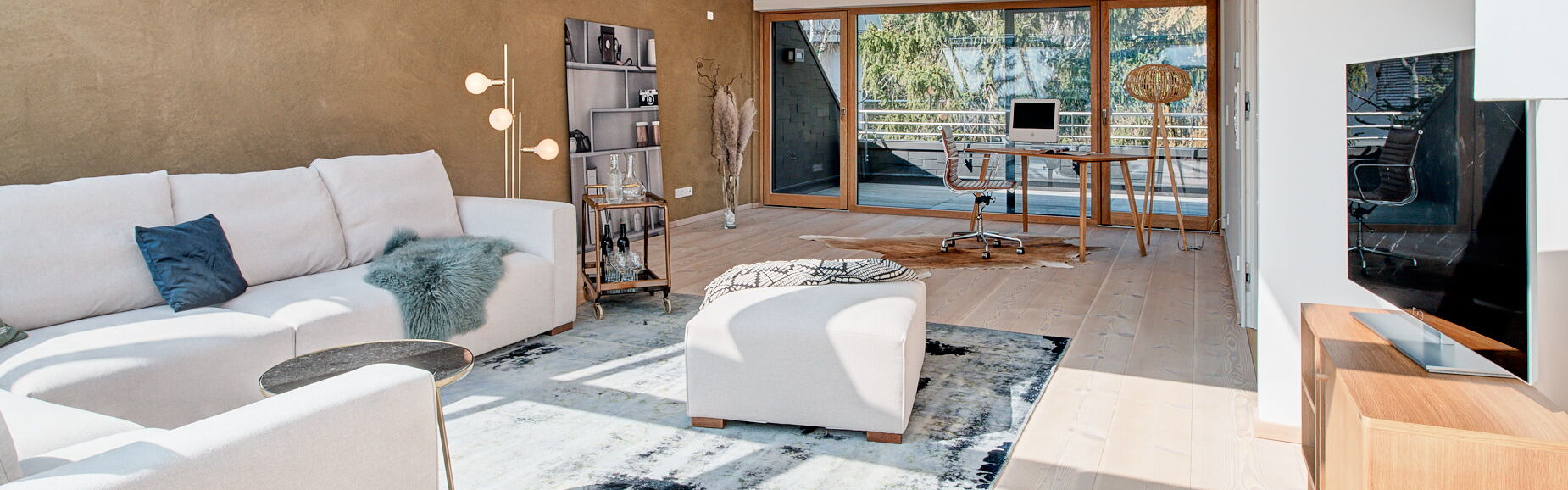 Wohnraum im Dach mit Lehmwand und großem L-Sofa in beige und blauem Teppich